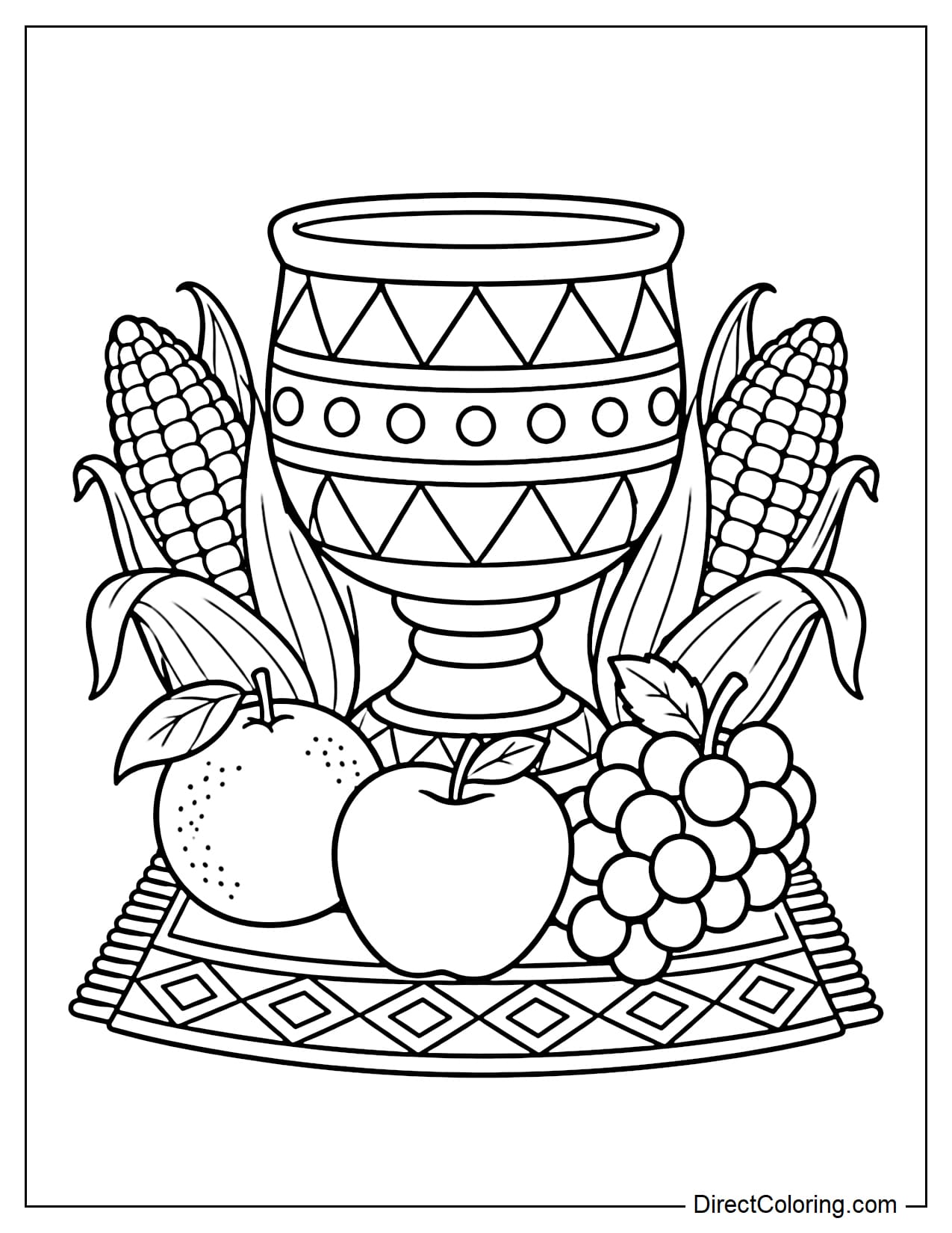 A large Kikombe cha Umoja unity cup sits on a Mkeka mat, flanked by two ears of corn, with an apple, an orange, and a bunch of grapes in front.